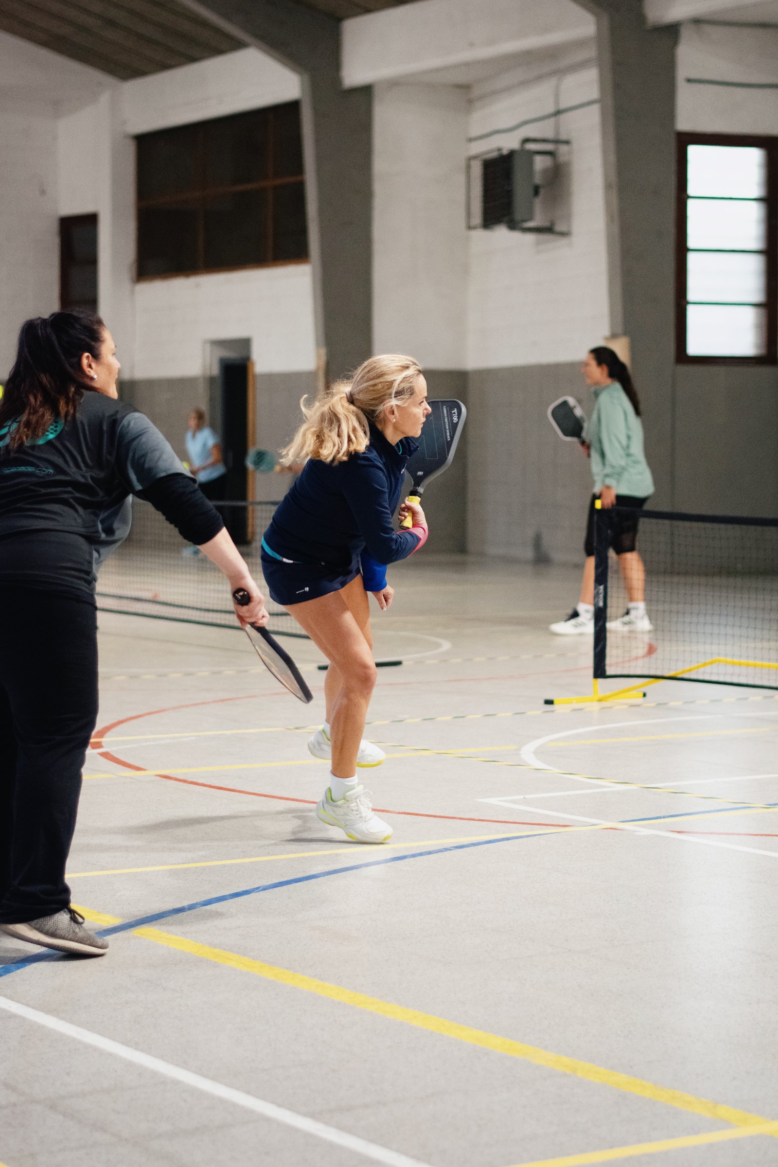 Jugadoras adultas participando en una jornada de pickleball en pabellón